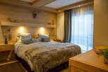 Cozy bedroom with wooden walls and a plush bed, featuring a faux fur throw and decorative pillows.