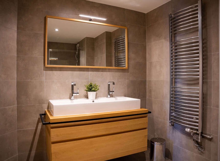 Modern bathroom with double sink vanity, sleek mirror, and curved heated towel rack.