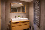 Modern bathroom with double sink vanity, sleek mirror, and curved heated towel rack.