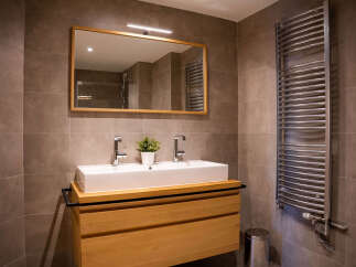 Modern bathroom with double sink vanity, sleek mirror, and curved heated towel rack.