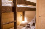 Cozy bunk beds with plush bedding and a teddy bear add a touch of whimsy to this charming wooden-paneled room.