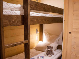 Cozy bunk beds with plush bedding and a teddy bear add a touch of whimsy to this charming wooden-paneled room.