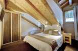 Discover the charm of this cozy bedroom with its unique sloped ceiling and exposed wooden beams.