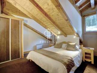Discover the charm of this cozy bedroom with its unique sloped ceiling and exposed wooden beams.