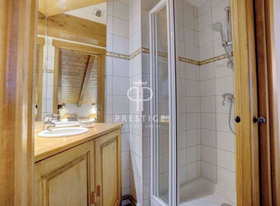 Discover a charming bathroom with a rustic wooden vanity and a sleek glass shower enclosure.
