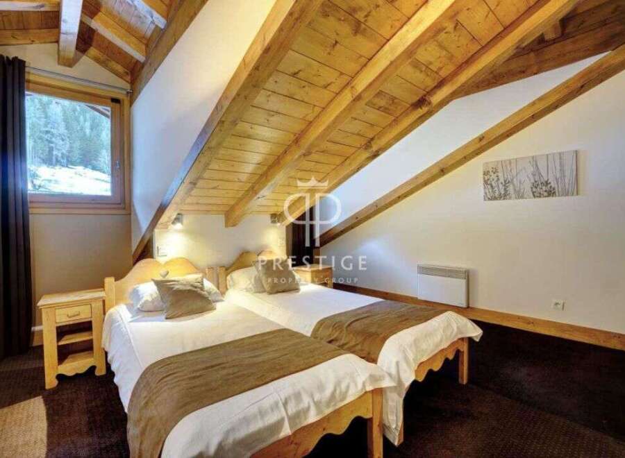 Discover the charm of this cozy bedroom, featuring a unique sloped ceiling with exposed wooden beams.
