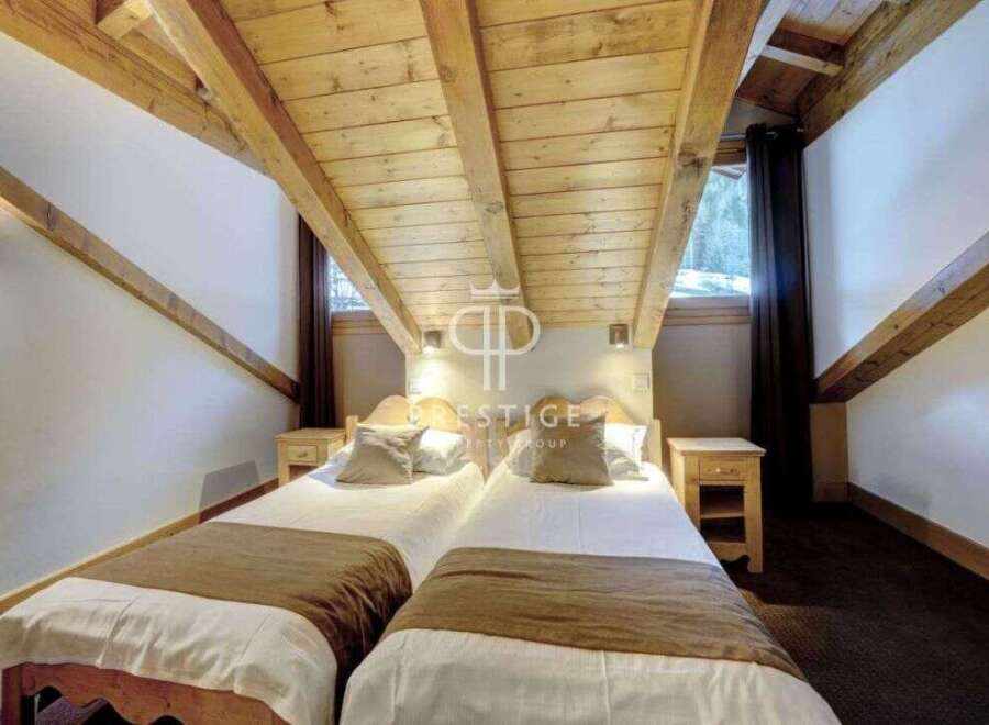 Discover a cozy bedroom with a unique sloped ceiling and exposed wooden beams, creating a warm and inviting atmosphere.