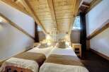 Discover a cozy bedroom with a unique sloped ceiling and exposed wooden beams, creating a warm and inviting atmosphere.