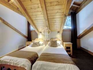 Discover a cozy bedroom with a unique sloped ceiling and exposed wooden beams, creating a warm and inviting atmosphere.