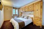 Cozy bedroom with wooden furniture and a comfortable bed.