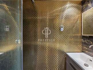 Step into luxury with this stunning bathroom featuring a unique gold mosaic tile design.