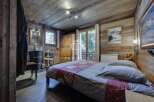 Experience rustic charm in this cozy bedroom, featuring wooden walls and a warm ambiance.