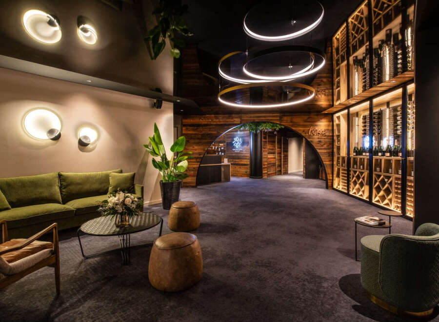 This luxurious hotel lobby boasts a stunning wine cellar, plush seating areas, and modern lighting fixtures.
