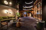 This luxurious hotel lobby boasts a stunning wine cellar, plush seating areas, and modern lighting fixtures.