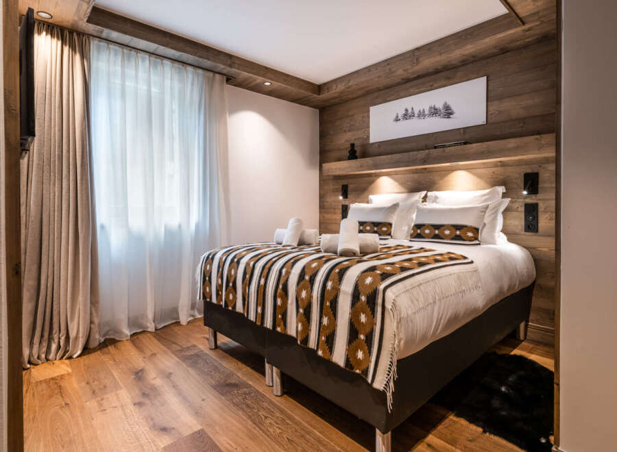 This stunning bedroom boasts a cozy and luxurious atmosphere, featuring a plush bed with a stylish throw blanket and crisp white linens.