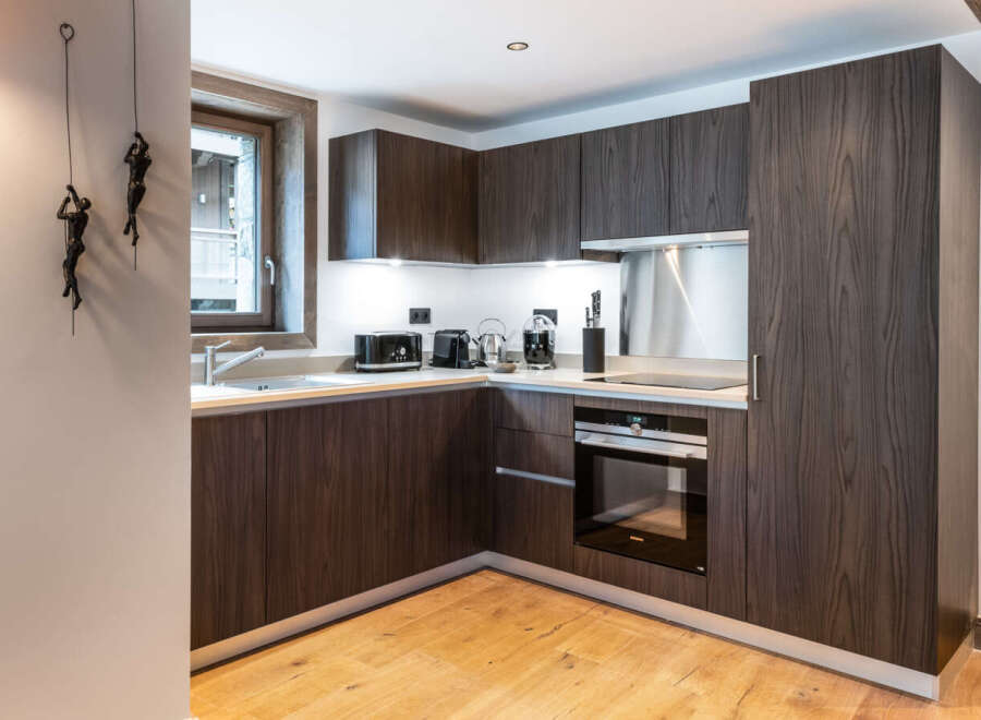 Modern kitchen with dark wood cabinets and integrated appliances.