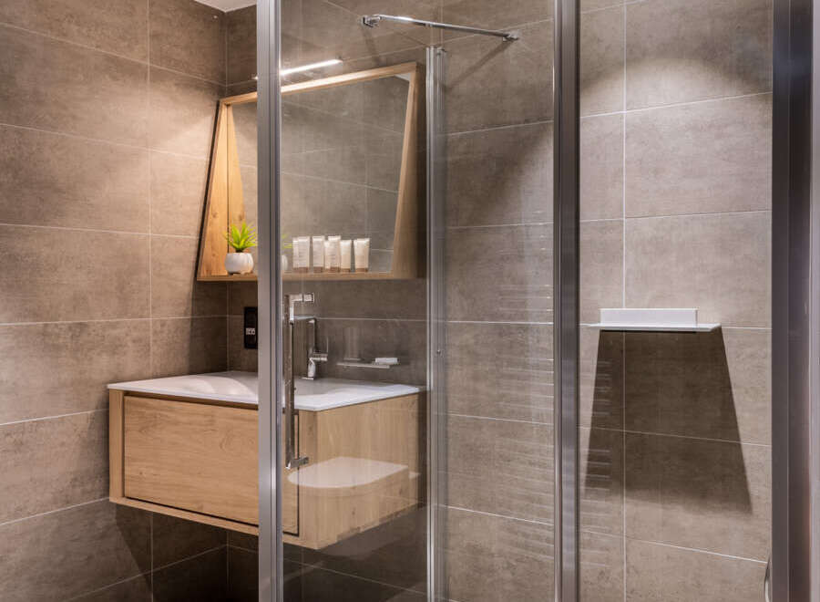 Modern bathroom with a walk-in shower, sleek wooden vanity, and stylish mirror.