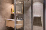 Modern bathroom with a walk-in shower, sleek wooden vanity, and stylish mirror.