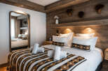 Cozy bedroom with a wooden wall and a comfortable bed featuring a patterned throw blanket.