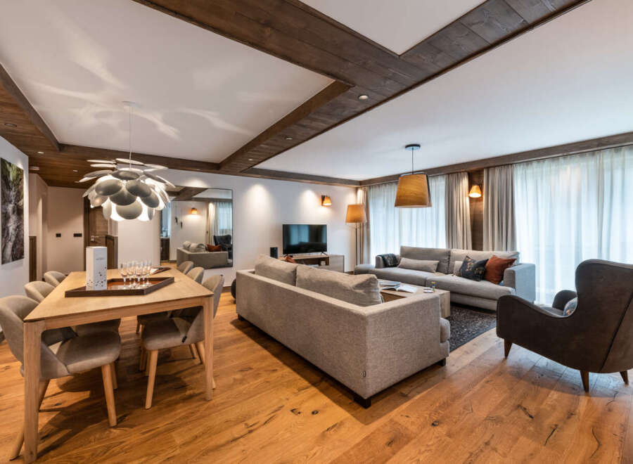 This stunning apartment boasts a spacious open-plan living area with hardwood floors, a modern dining table, and comfortable seating.