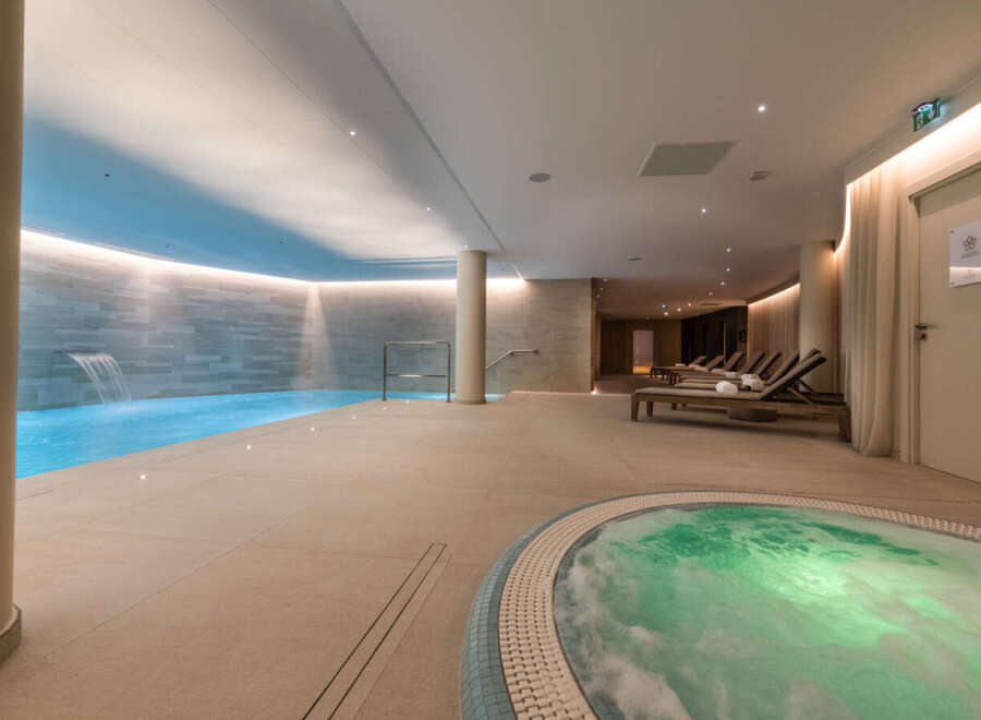 Indulge in tranquility at our luxurious spa, featuring a pristine indoor pool with a soothing waterfall and a relaxing jacuzzi.