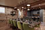 This stunning chalet boasts a spacious dining area with a long wooden table, surrounded by plush green velvet chairs, perfect for intimate gatherings.