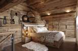 This stunning bedroom boasts a rustic-chic design with exposed wood beams, walls, and floors, creating a warm and inviting atmosphere.