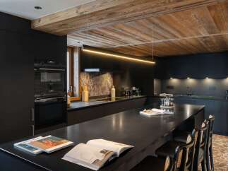 This modern kitchen boasts sleek black cabinetry and a stunning wooden ceiling, creating a sophisticated and inviting atmosphere.