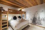 This cozy bedroom features a unique bunk bed design with a warm wooden aesthetic, perfect for a family or group getaway.