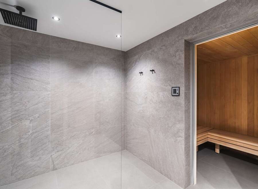 Step into luxury with this stunning bathroom featuring a modern shower and a relaxing sauna.