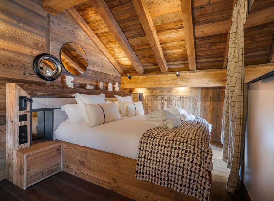 Experience rustic luxury in this stunning bedroom featuring exposed wooden beams and walls, creating a warm and inviting atmosphere.