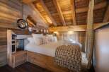 Experience rustic luxury in this stunning bedroom featuring exposed wooden beams and walls, creating a warm and inviting atmosphere.