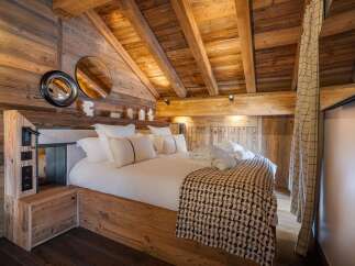 Experience rustic luxury in this stunning bedroom featuring exposed wooden beams and walls, creating a warm and inviting atmosphere.