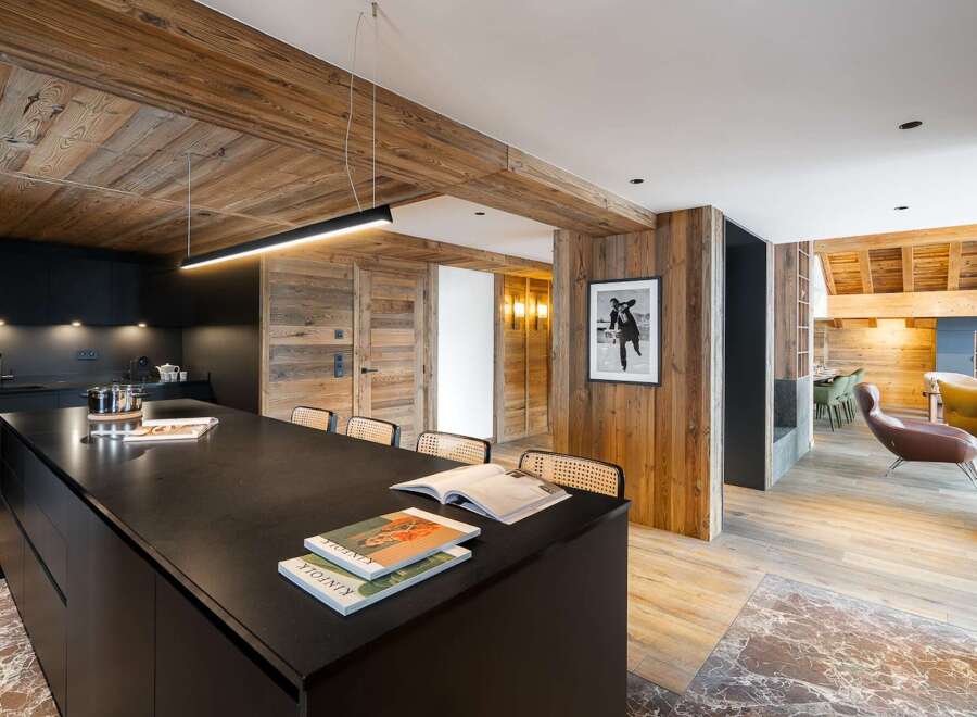 Experience luxury living in this stunning property featuring a modern kitchen with a sleek black island and wooden accents.