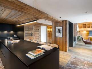 Experience luxury living in this stunning property featuring a modern kitchen with a sleek black island and wooden accents.