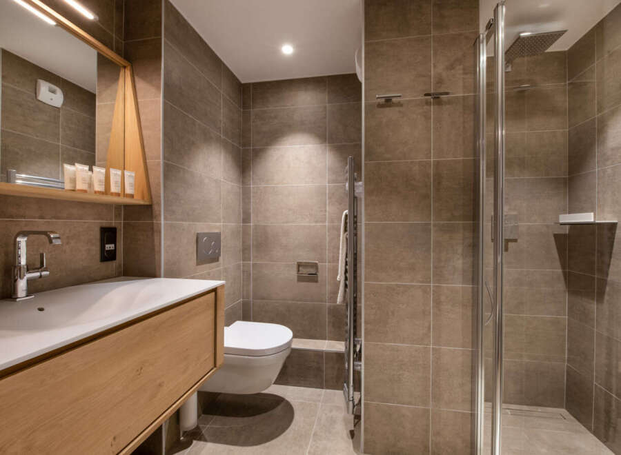 Modern bathroom with a walk-in shower, stylish wooden vanity, and sleek fixtures.