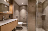 Modern bathroom with a walk-in shower, stylish wooden vanity, and sleek fixtures.