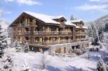 This stunning chalet-style apartment building offers luxurious ski-in/ski-out living in a breathtaking snowy mountain setting.
