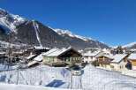 Experience the charm of a snow-covered village nestled against majestic mountains.