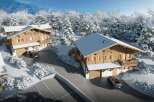 Experience the ultimate winter getaway in these stunning wooden chalets nestled in a snowy landscape.