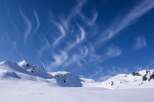 Experience the serene beauty of a snow-covered mountain landscape under a vibrant blue sky.