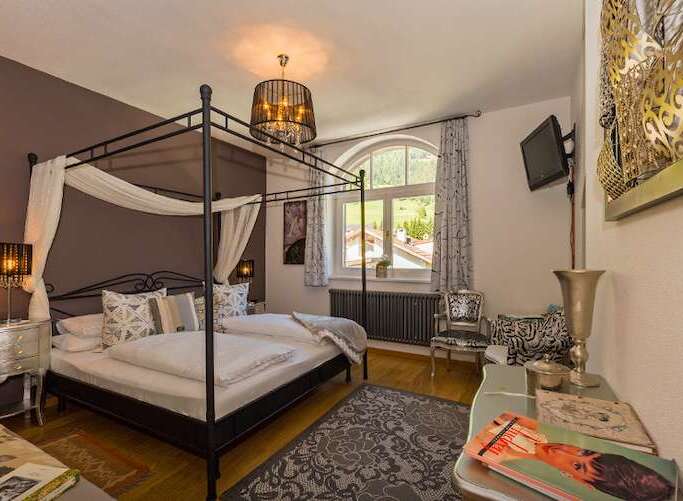 Experience luxury in this elegant bedroom featuring a stunning four-poster bed and a stylish chandelier.