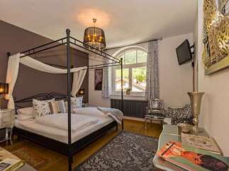 Experience luxury in this elegant bedroom featuring a stunning four-poster bed and a stylish chandelier.