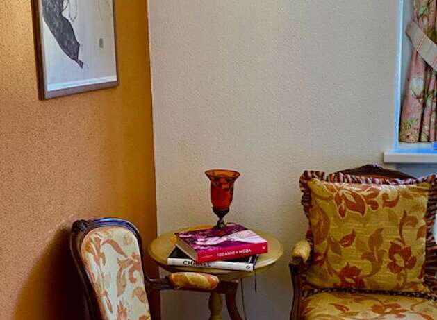 Discover the charm of this cozy corner, featuring elegant seating and a vintage sewing machine wall decor.