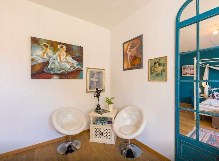 Discover a charming corner with artistic flair! This space features elegant white chairs, perfect for relaxation.