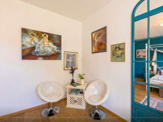 Discover a charming corner with artistic flair! This space features elegant white chairs, perfect for relaxation.