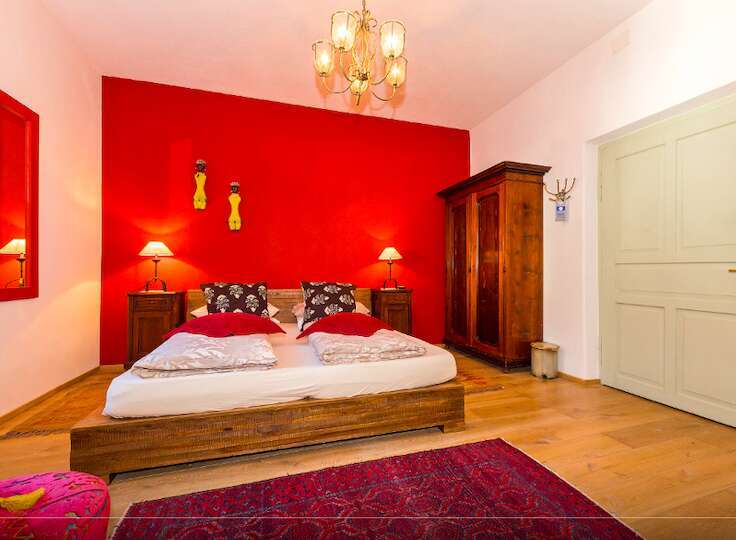 Discover a cozy bedroom with a vibrant red accent wall, creating a warm and inviting atmosphere.