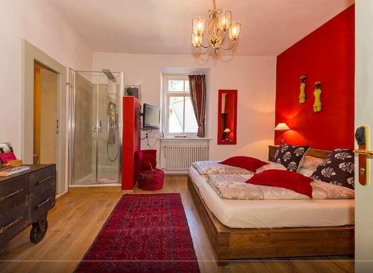 This charming bedroom boasts a vibrant red accent wall, creating a warm and inviting atmosphere.