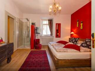 This charming bedroom boasts a vibrant red accent wall, creating a warm and inviting atmosphere.