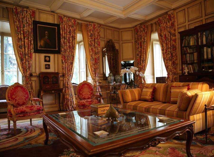 This luxurious living room boasts rich, wood-paneled walls, elegant floral curtains, and antique furnishings.
